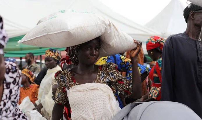 Una mujer recibe una bolsa de alimentos del gobierno durante la distribución de alimentos por parte del gobierno para amortiguar el alto costo de vida en Abuja Nigeria