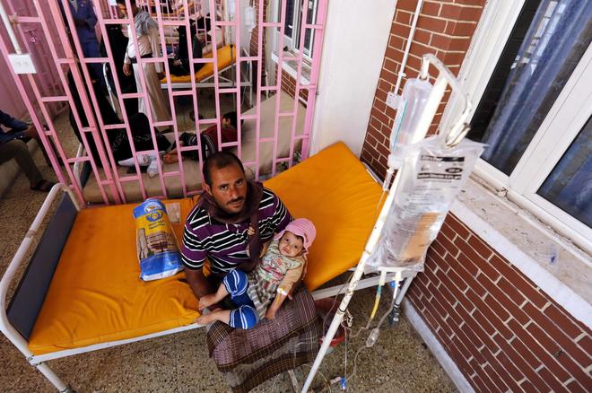 Un hombre sostiene a su hijo infectado de cólera en un hospital de Yemen